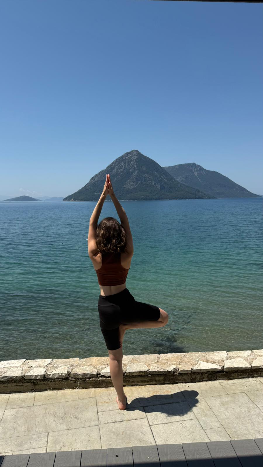 Clarine en posture de l'arbre face à la mer, les montagnes à l'horizon